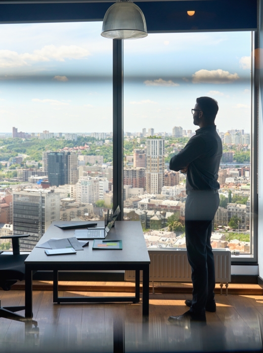 Silhouette of indian confident successful businessman thinking imagining future corporate financial career standing at office near window of high floor building with city view on big urban center.